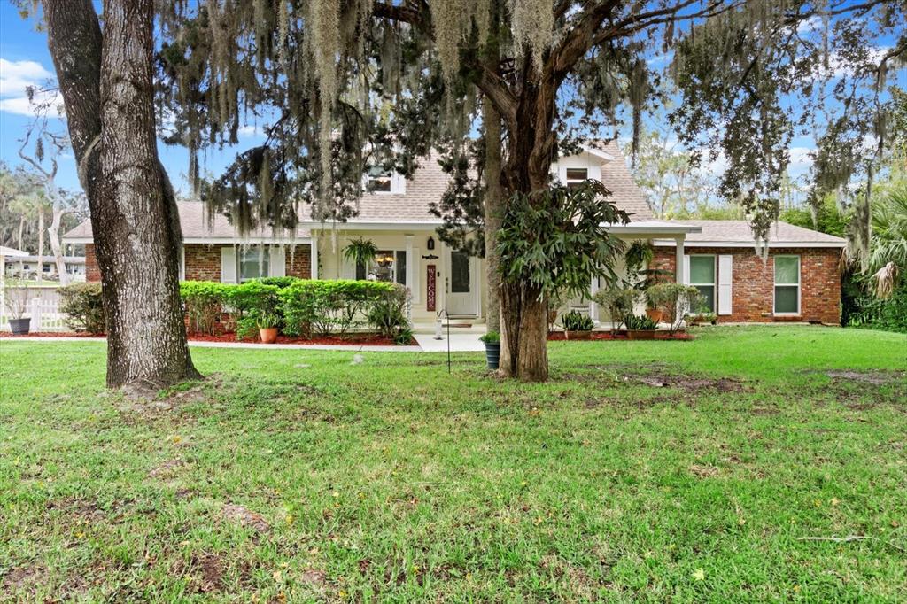 A single-story brick house with a front porch, surrounded by large trees with Spanish moss — 1110 N RICE TERRACE, CRYSTAL RIVER, FL