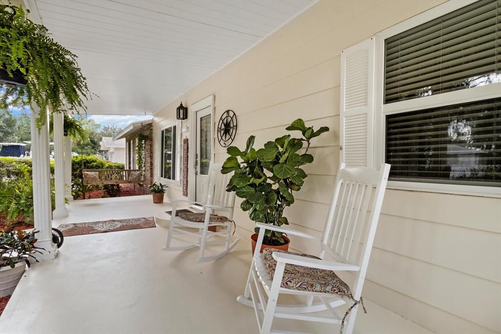 A covered front porch features two white rocking chairs, a potted plant, and a hanging fern — 1110 N RICE TERRACE, CRYSTAL RIVER, FL