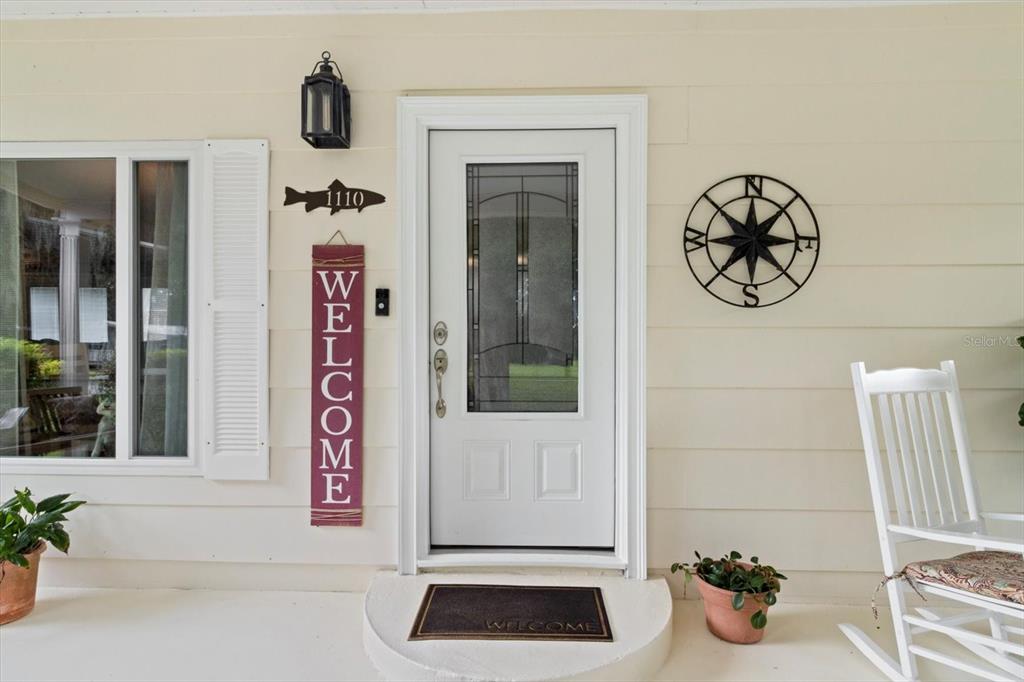 A front porch features a white door, a welcome sign, and a compass wall decoration — 1110 N RICE TERRACE, CRYSTAL RIVER, FL
