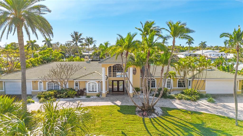 A single-story house with a tiled roof, white columns, and palm trees in the front yard — 482 HERMOSITA DRIVE, ST PETE BEACH, FL