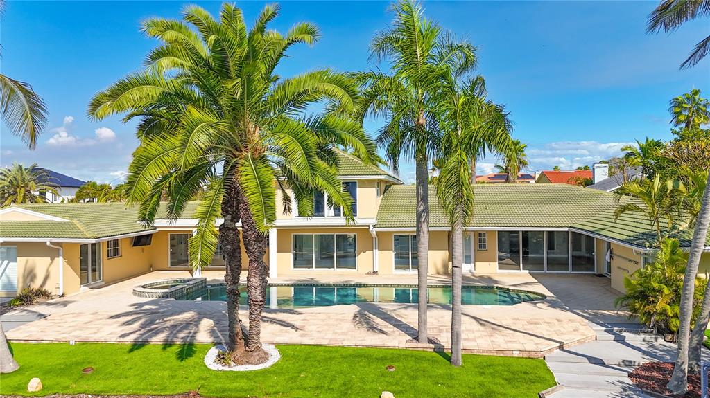 A two-story house with a green tile roof, a swimming pool, and several palm trees — 482 HERMOSITA DRIVE, ST PETE BEACH, FL