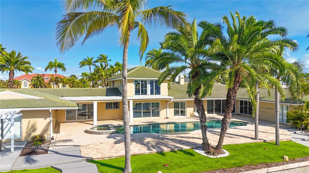 A two-story house with a green tile roof, swimming pool, and palm trees — 482 HERMOSITA DRIVE, ST PETE BEACH, FL