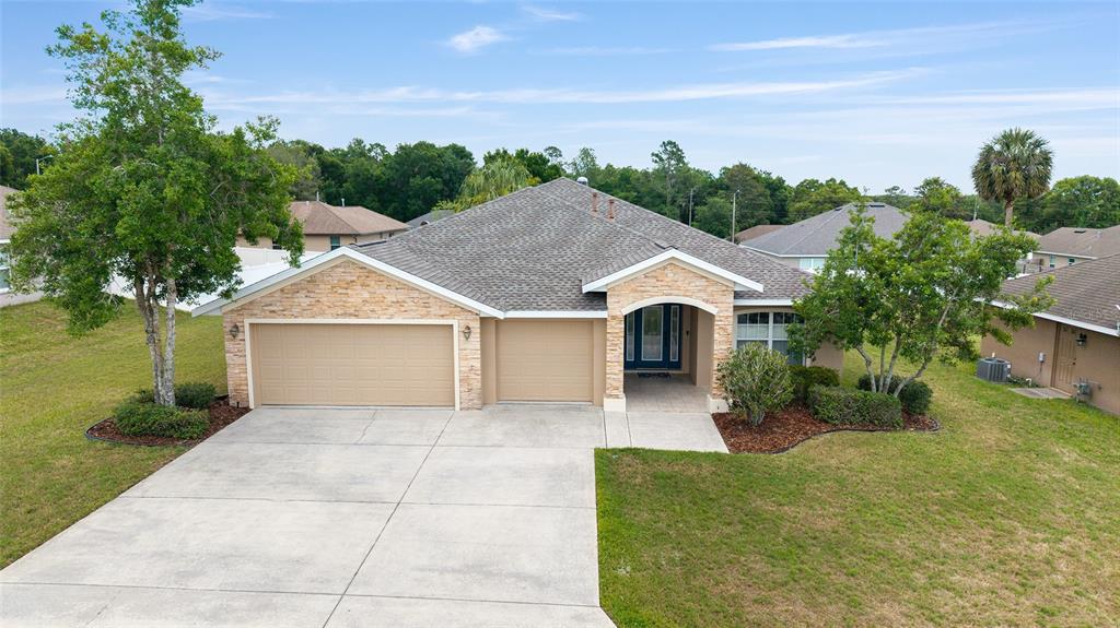 A single-story house with a stone facade, two-car garage, and a concrete driveway — 915 SE 69TH AVENUE, OCALA, FL