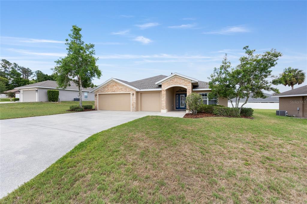 A single-story house with a stone facade, a three-car garage, and a paved driveway — 915 SE 69TH AVENUE, OCALA, FL