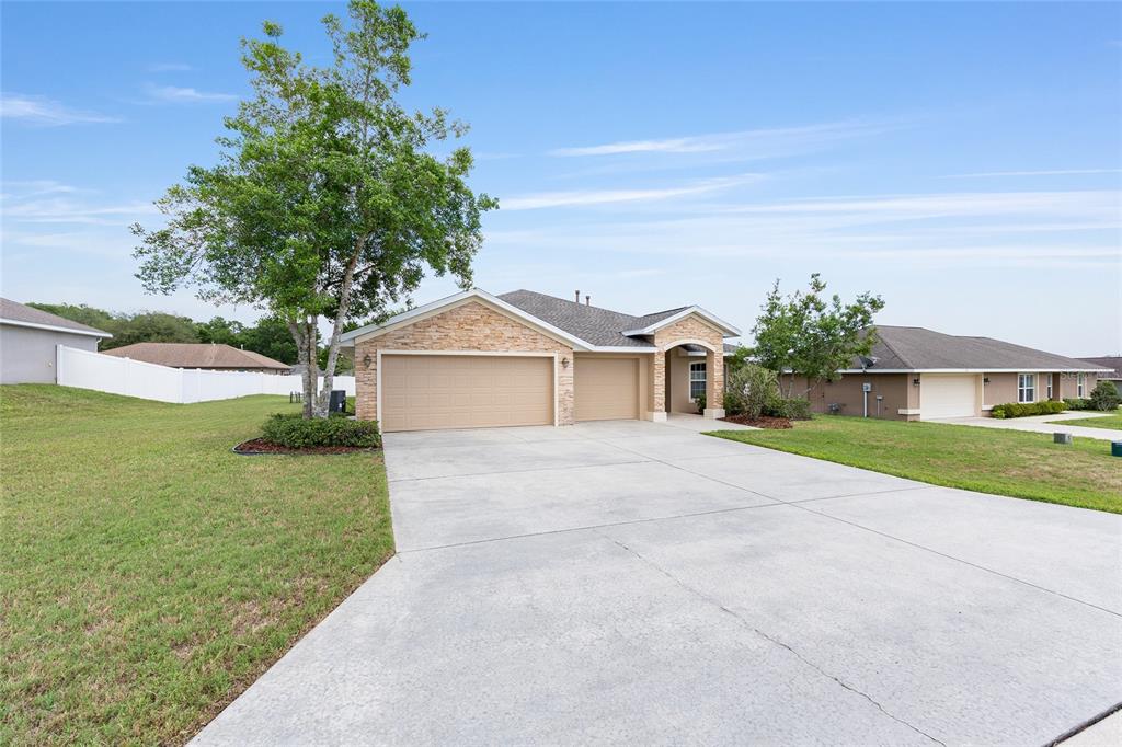 A single-story house with a stone facade, a three-car garage, and a concrete driveway — 915 SE 69TH AVENUE, OCALA, FL