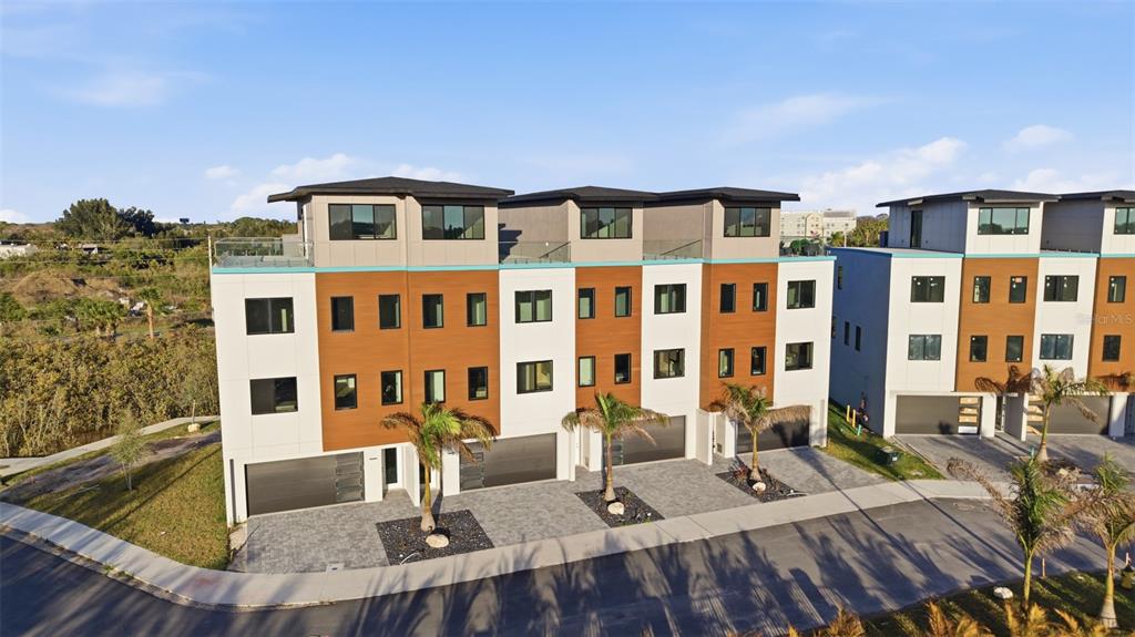 An exterior view of a modern three-story townhouse complex with attached garages and palm trees — 5968 AQUA RESERVE BOULEVARD, NEW PORT RICHEY, FL