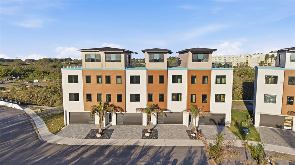 A multi-story townhouse complex features modern architecture with wood-paneled accents and attached garages — 5968 AQUA RESERVE BOULEVARD, NEW PORT RICHEY, FL