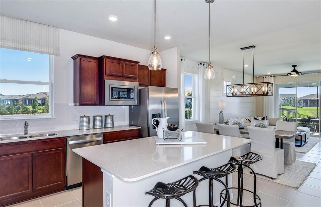 A kitchen with dark wood cabinets, stainless steel appliances, and a white quartz island — 14761 SUNLIT CIRCLE, PARRISH, FL