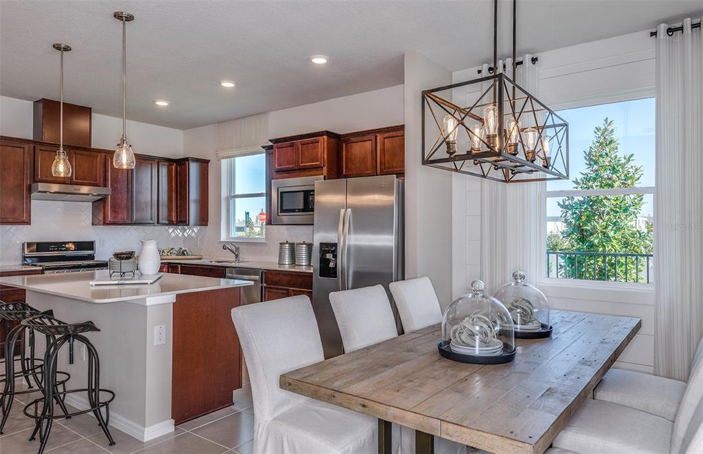 A kitchen with wood cabinets and a dining area featuring a rustic table and chandelier — 14761 SUNLIT CIRCLE, PARRISH, FL