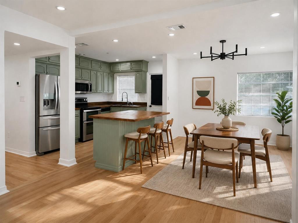 A kitchen with sage green cabinets and a wood island opens into a dining area — 630 TAM O SHANTER DRIVE, ORLANDO, FL