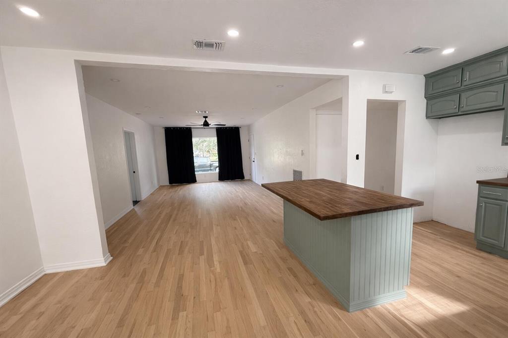 An open-concept room features light wood flooring, a kitchen island, and gray cabinetry — 630 TAM O SHANTER DRIVE, ORLANDO, FL
