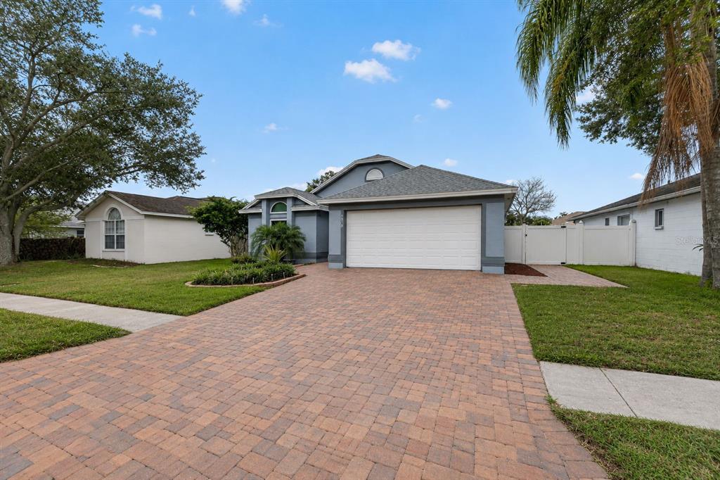 A single-story house with a paved driveway, a two-car garage, and a white fence — 5910 BUTTON QUAIL COURT, TAMPA, FL