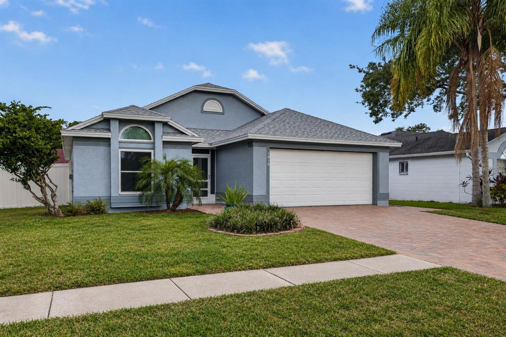 A blue single-story house with a two-car garage, a paved driveway, and a front lawn — 5910 BUTTON QUAIL COURT, TAMPA, FL