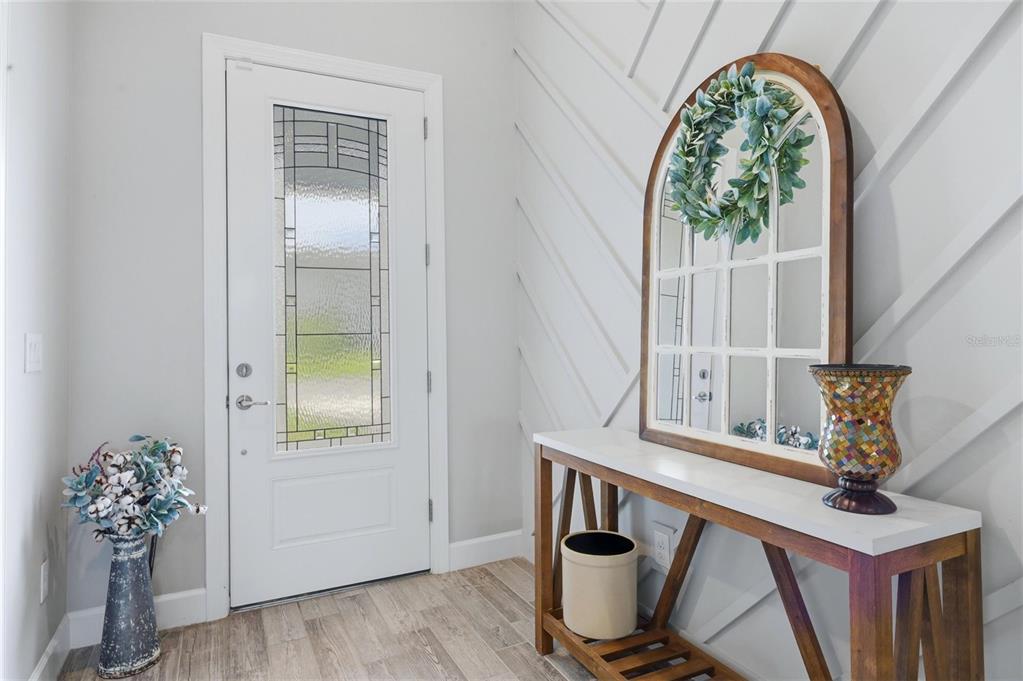 An entryway features a white door, wood-look tile flooring, and a console table with decor — 12311 BLUE HILL TRAIL, BRADENTON, FL