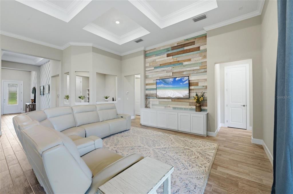 A living room features a light-colored sectional sofa, a wood-paneled accent wall, and tile flooring — 12311 BLUE HILL TRAIL, BRADENTON, FL
