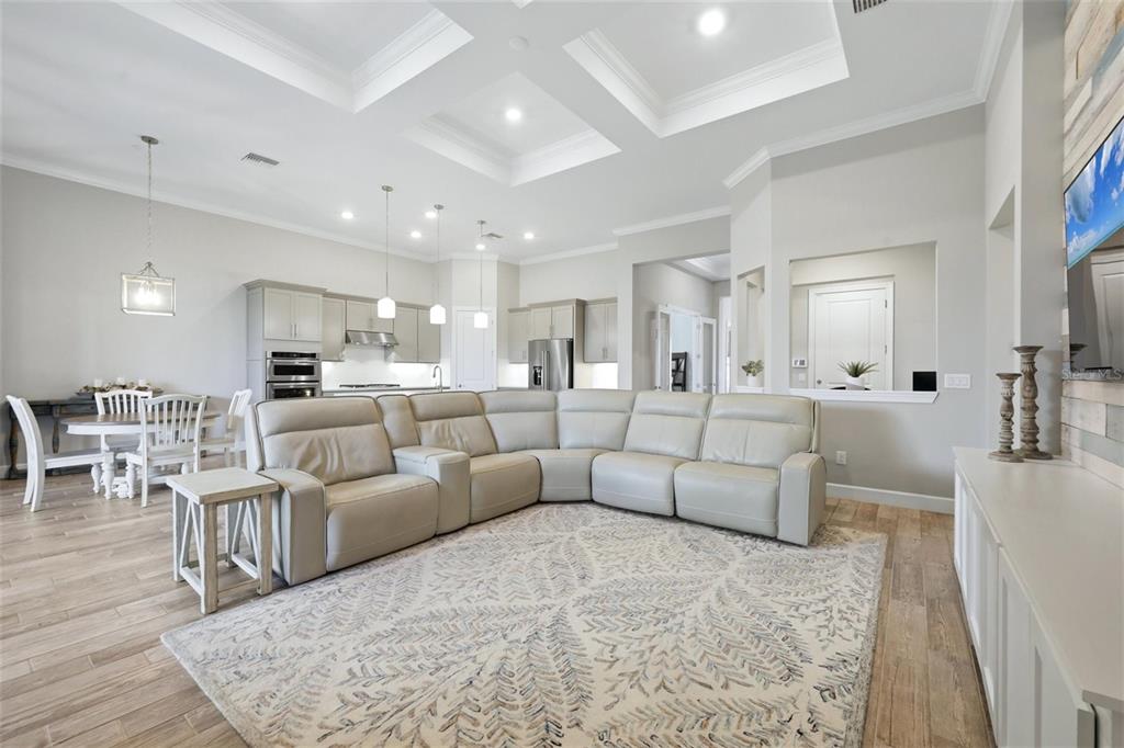 A spacious open-concept living room features a large sectional sofa, dining area, and kitchen — 12311 BLUE HILL TRAIL, BRADENTON, FL
