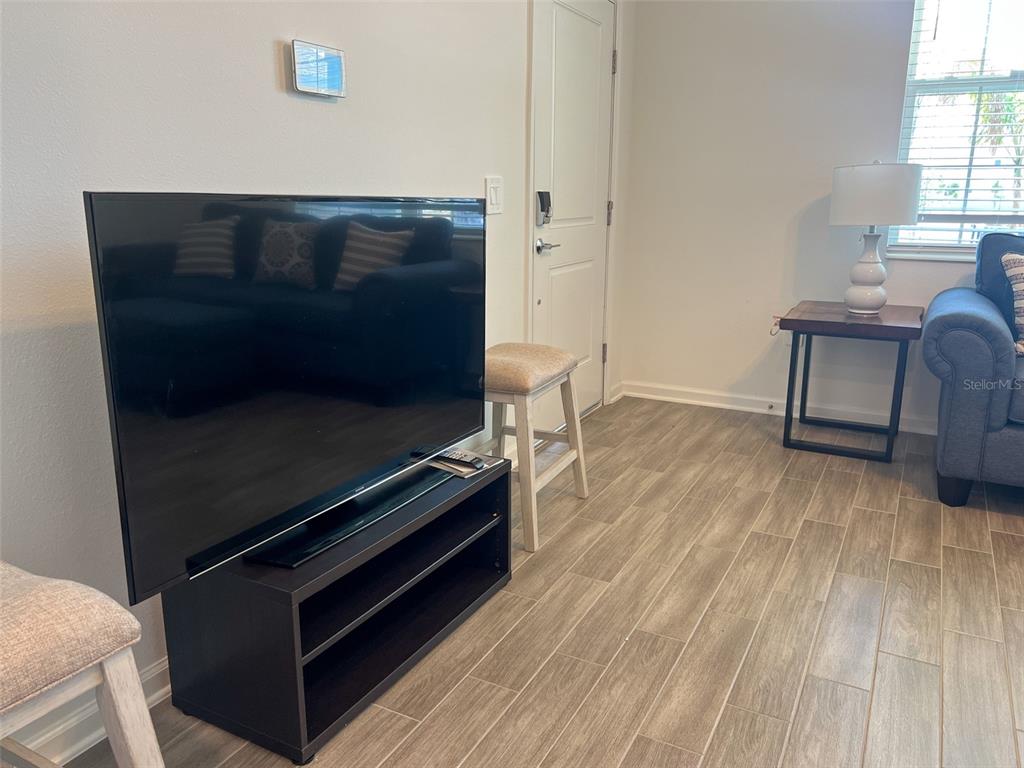 A living room features a television on a black stand, tile flooring, and a sofa — 6488 NEEDLE WAY, ST CLOUD, FL