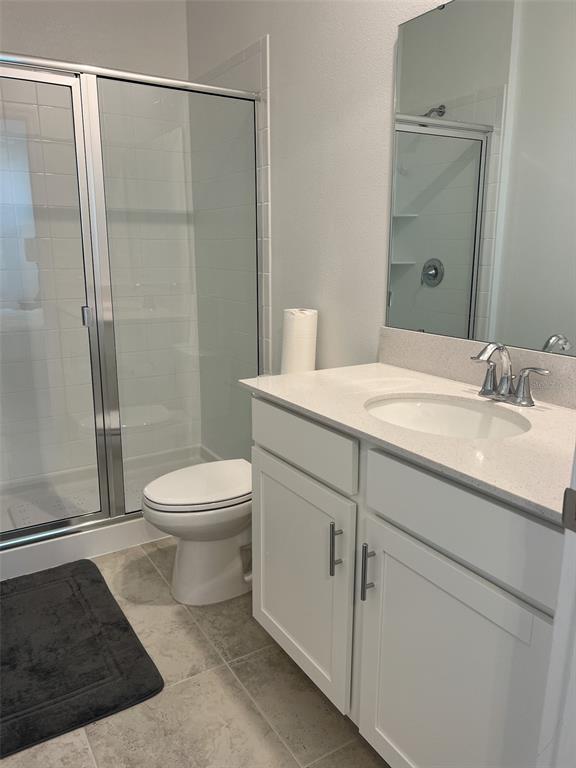 A bathroom features a white vanity, a glass-enclosed shower, and a toilet on tiled flooring — 6488 NEEDLE WAY, ST CLOUD, FL