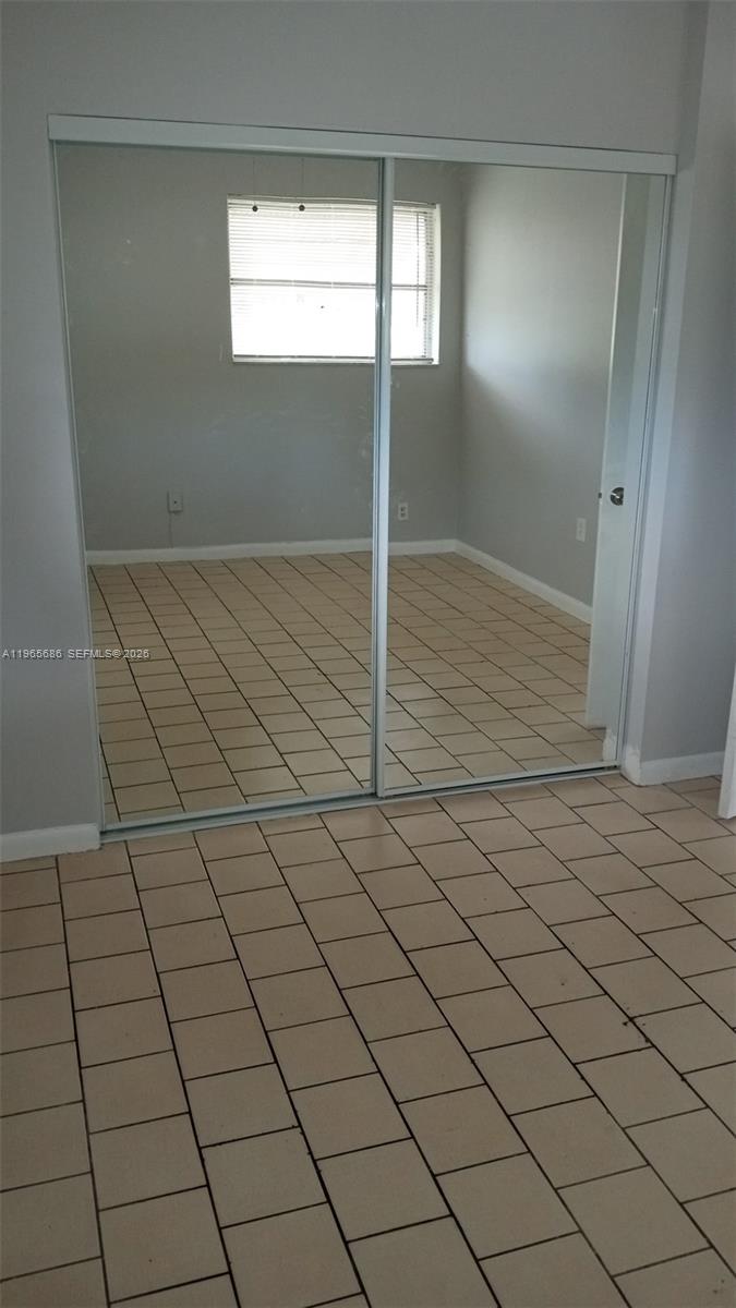 A room with light-colored tile flooring features a large sliding mirrored closet door — 1855 Cleveland St # A, Hollywood FL 33020, HOLLYWOOD, FL