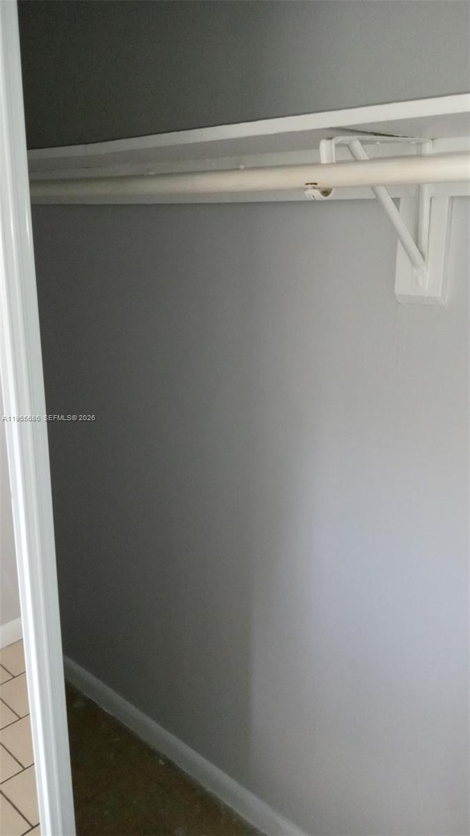 A closet interior features a white shelf and a metal hanging rod on gray walls — 1855 Cleveland St # A, Hollywood FL 33020, HOLLYWOOD, FL