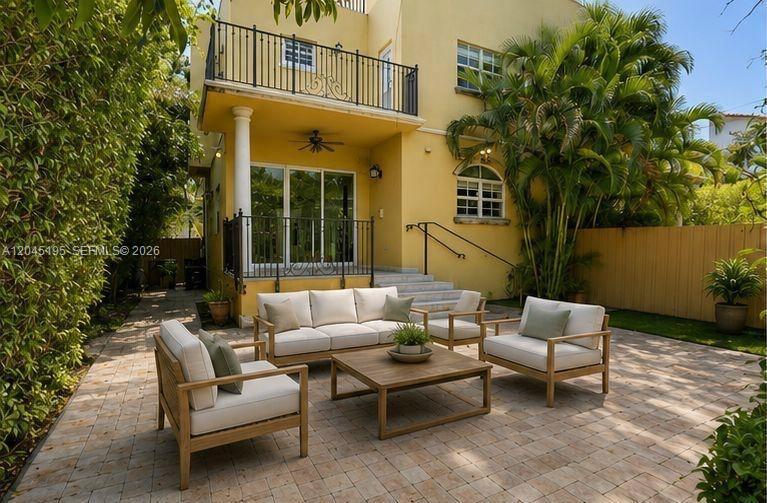 A patio with outdoor furniture sits in front of a yellow two-story house — 592 Fernwood Rd # B, Key Biscayne FL 33149, KEY BISCAYNE, FL