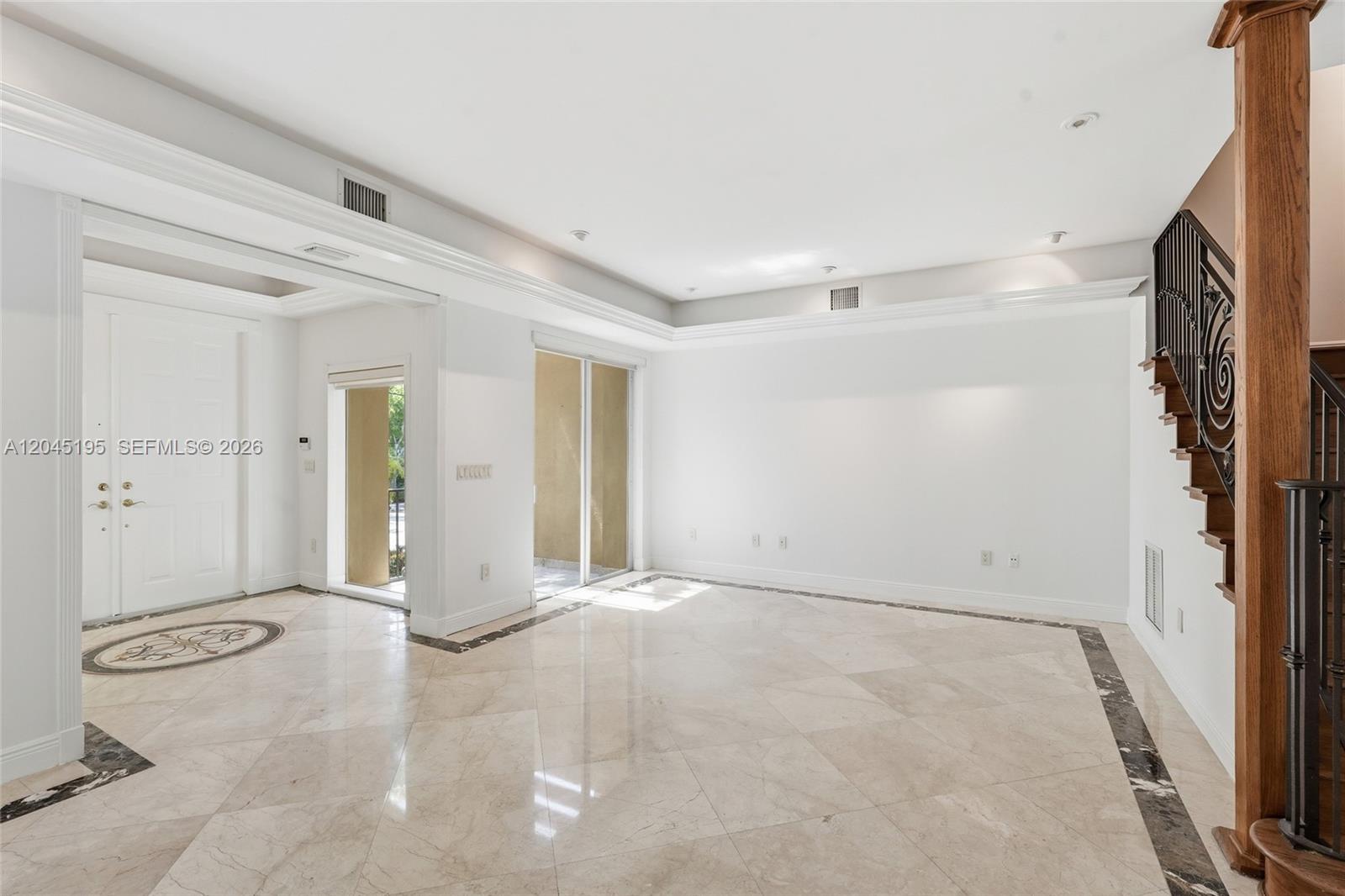 An empty living room features marble tile flooring, a staircase, and a white front door — 592 Fernwood Rd # B, Key Biscayne FL 33149, KEY BISCAYNE, FL
