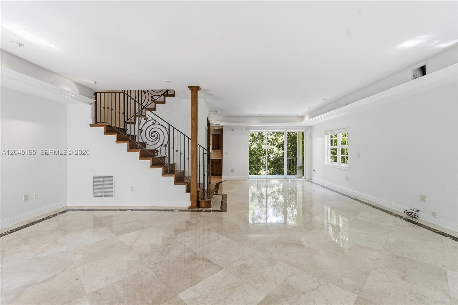 A spacious living room features marble tile floors, a decorative staircase, and sliding glass doors — 592 Fernwood Rd # B, Key Biscayne FL 33149, KEY BISCAYNE, FL