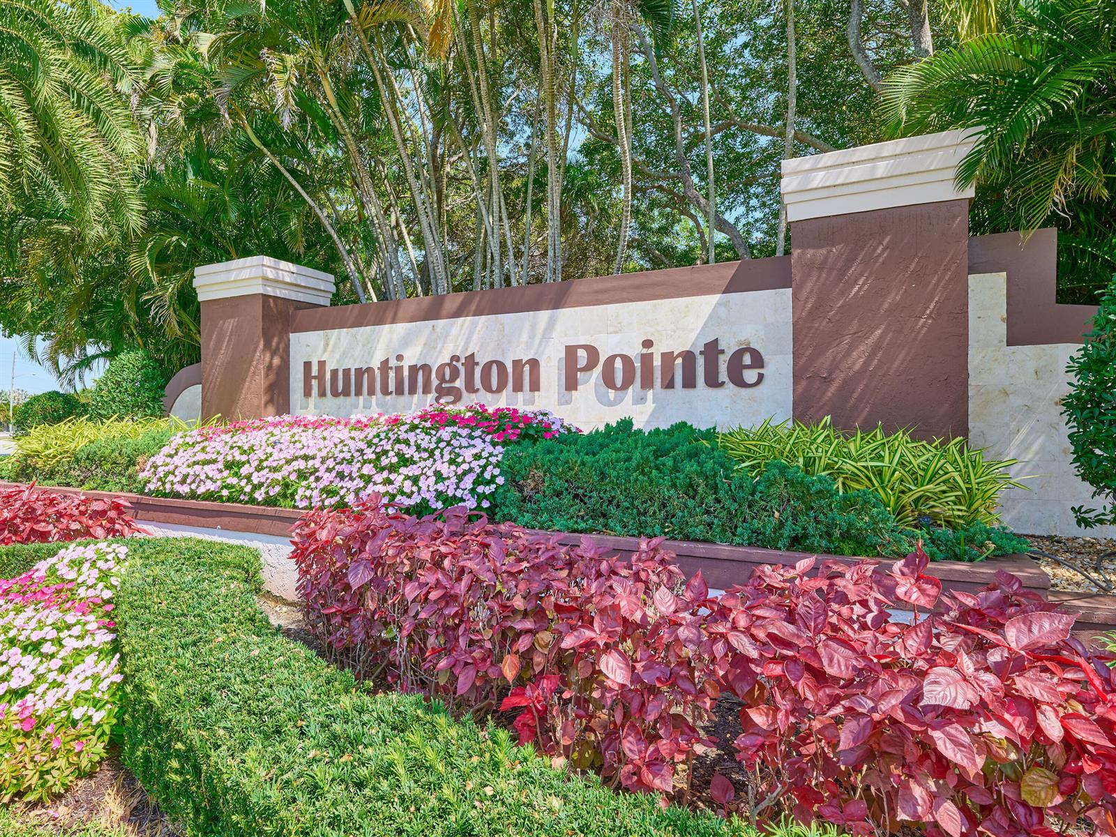 A stone monument sign for Huntington Pointe sits behind a garden of flowers and shrubs — 6193 Pointe Regal Circle # 306, Delray Beach FL 33484, DELRAY BEACH, FL
