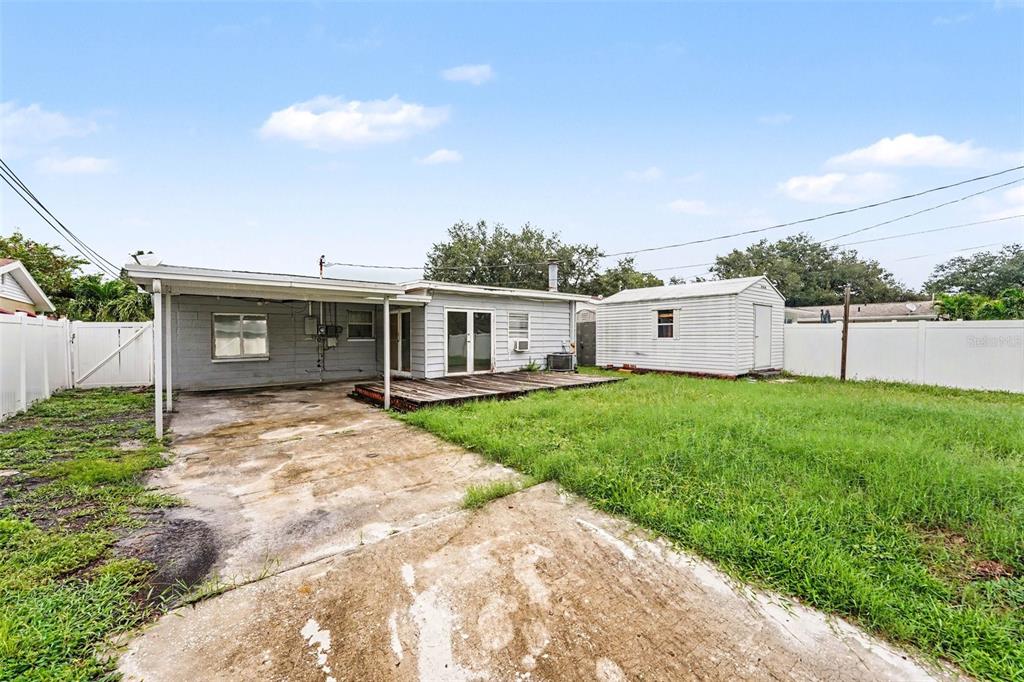 The exterior of a house features a concrete patio, a wooden deck, and a storage shed — 766 41ST AVENUE NE, ST PETERSBURG, FL