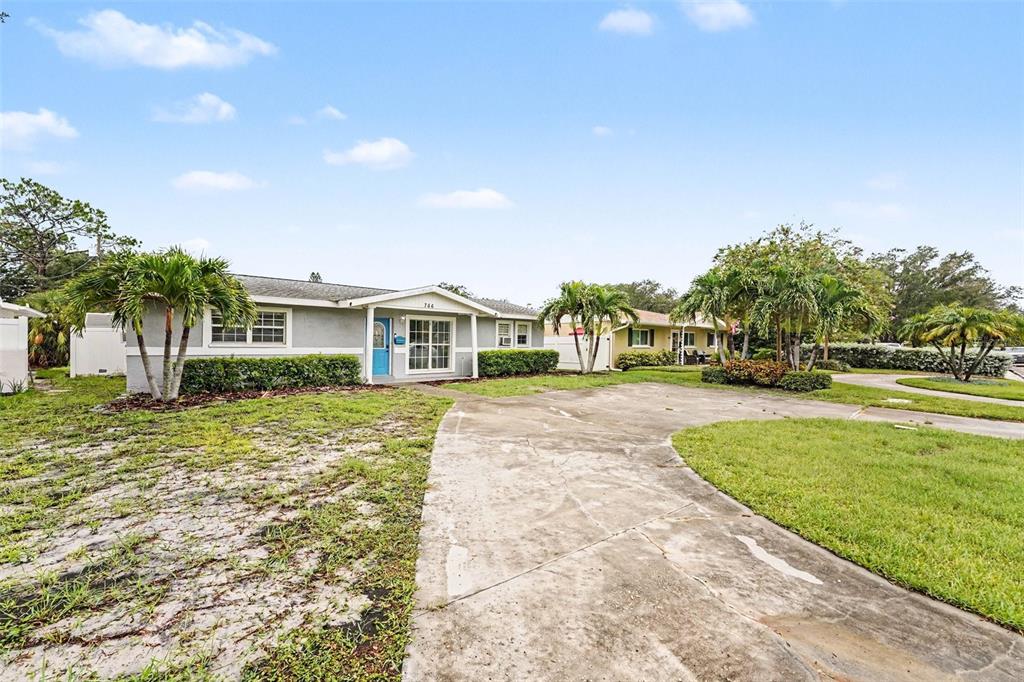 A single-story house with a concrete driveway, palm trees, and a blue front door — 766 41ST AVENUE NE, ST PETERSBURG, FL