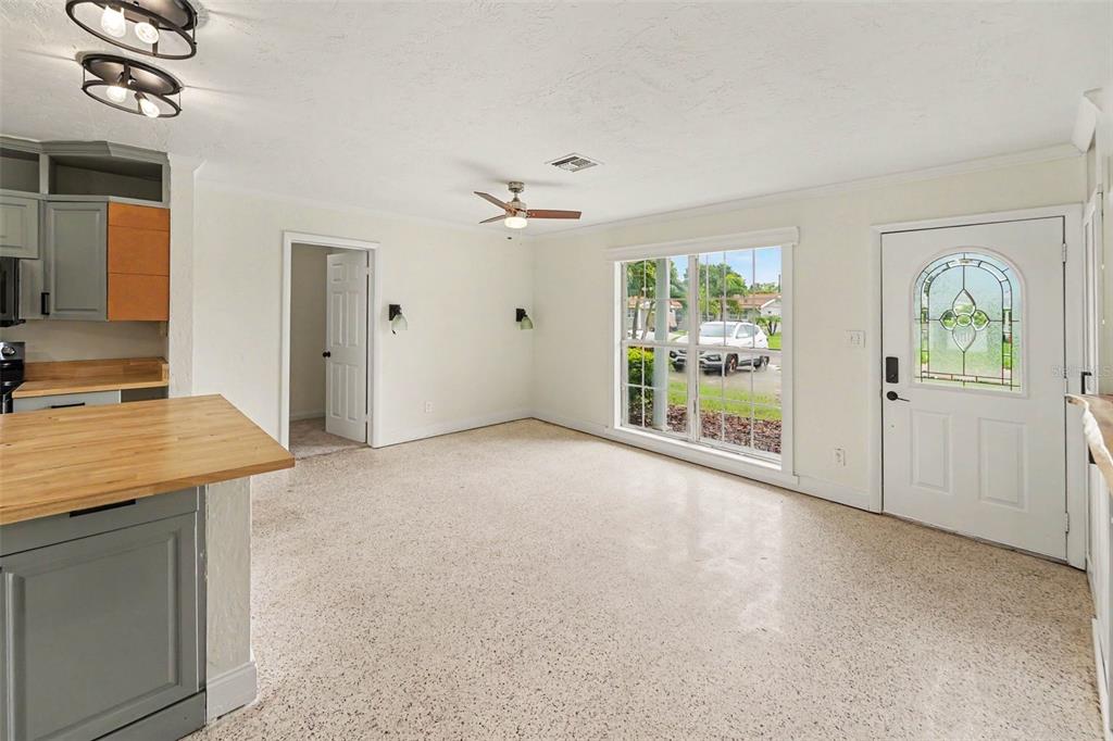 A bright living room features terrazzo flooring, a ceiling fan, and a front entry door — 766 41ST AVENUE NE, ST PETERSBURG, FL