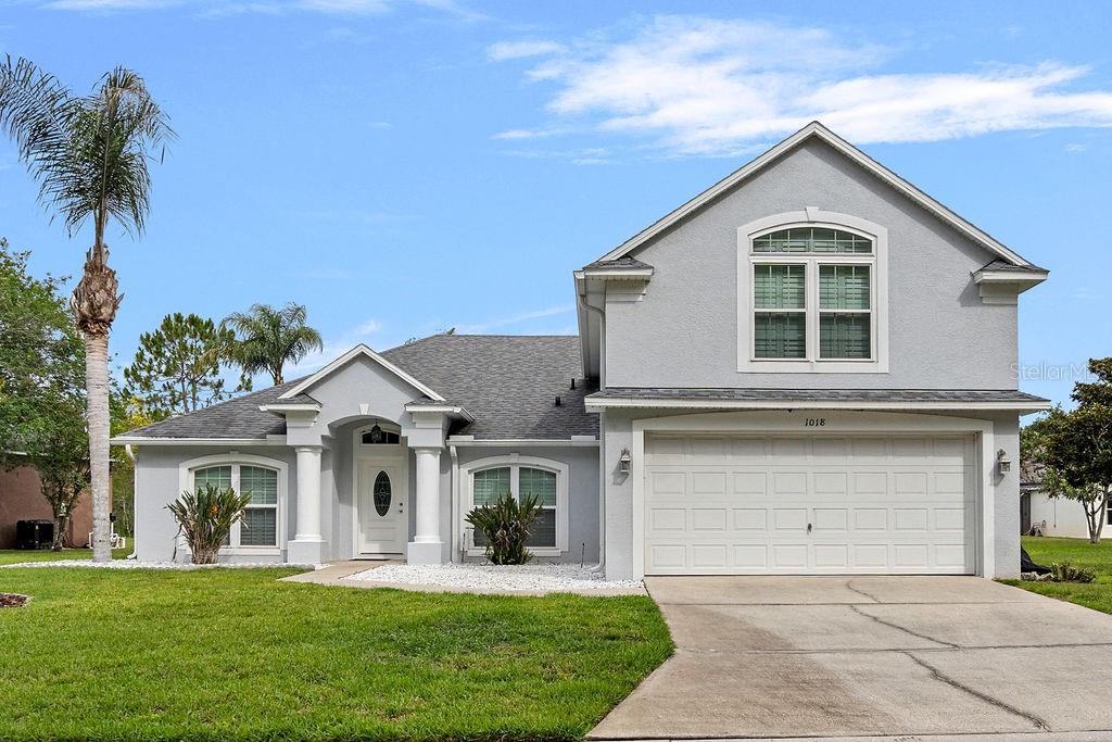 A two-story gray house with a white garage, columns at the entrance, and a palm tree — 1018 GRAND RESERVE DRIVE, DAVENPORT, FL