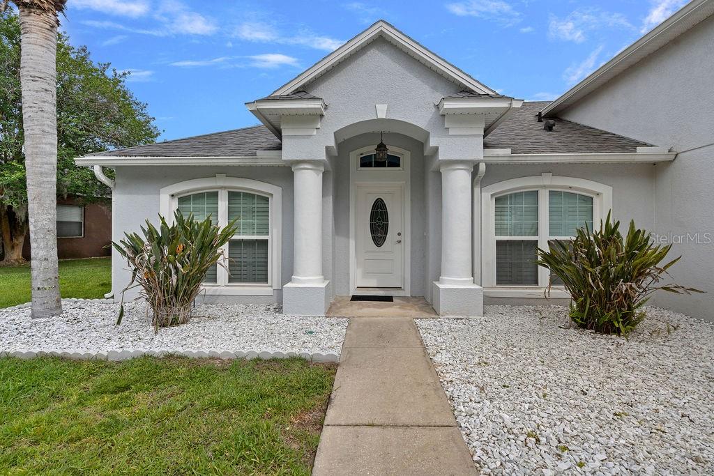 The exterior of a light gray house features a covered entryway with two white columns — 1018 GRAND RESERVE DRIVE, DAVENPORT, FL