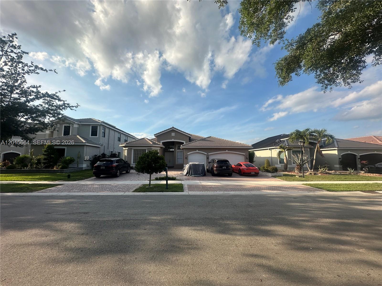A single-story house with a paved driveway and three parked cars sits under a blue sky — 18571 SW 44th St, Miramar FL 33029, MIRAMAR, FL