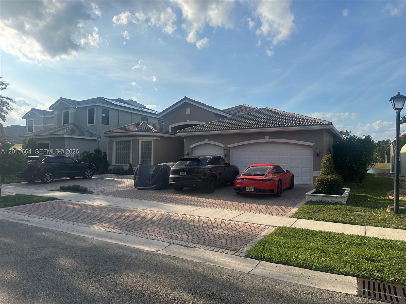 A suburban house exterior features a brick driveway with three parked cars and a garage — 18571 SW 44th St, Miramar FL 33029, MIRAMAR, FL