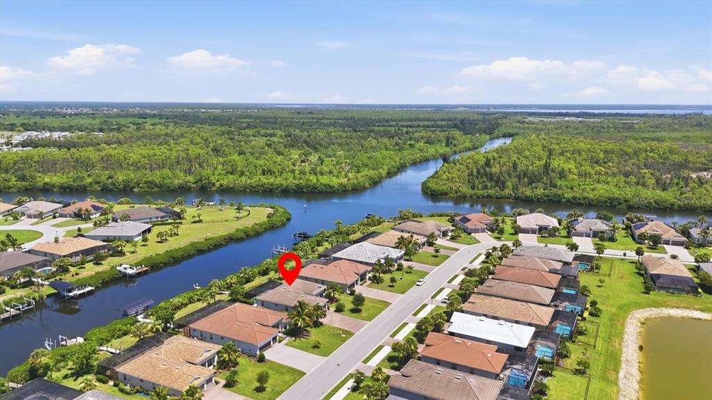 An aerial view shows a suburban neighborhood with houses situated along a winding canal — 15040 SPANISH POINT DRIVE, PORT CHARLOTTE, FL