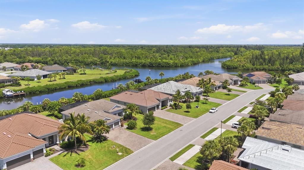 An aerial view shows suburban houses with tiled roofs situated along a winding canal — 15040 SPANISH POINT DRIVE, PORT CHARLOTTE, FL