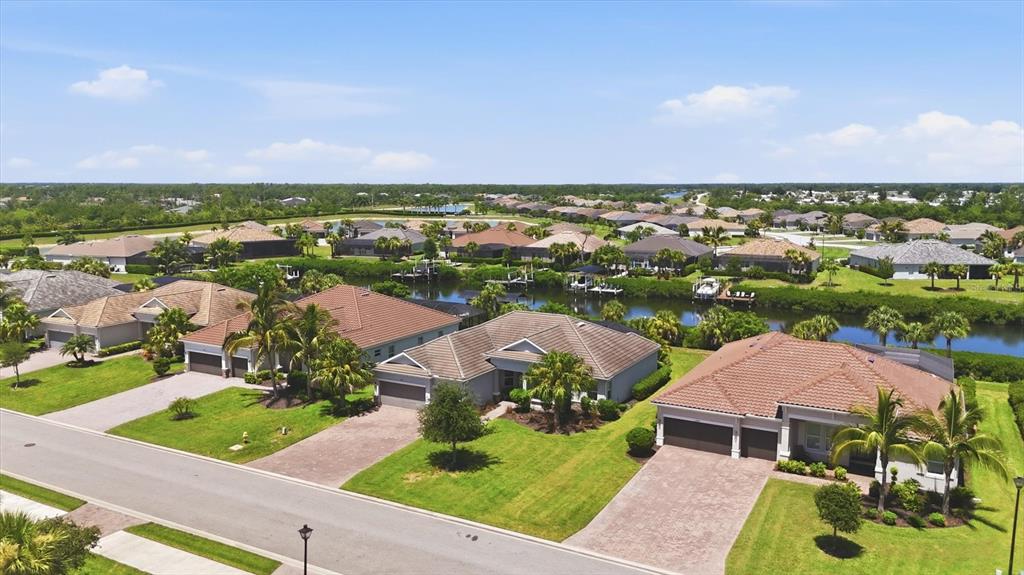An aerial view of a suburban neighborhood with houses, green lawns, and a central canal — 15040 SPANISH POINT DRIVE, PORT CHARLOTTE, FL