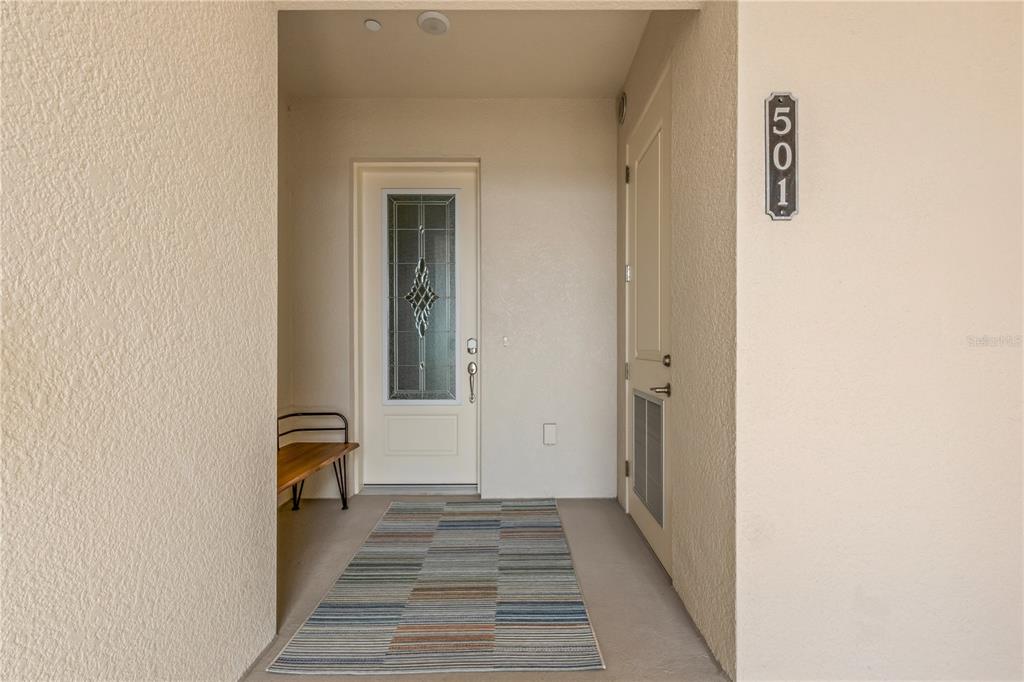 A covered entryway features a front door with a decorative glass insert and a rug — 505 TAMIAMI TRAIL N UNIT 501, VENICE, FL