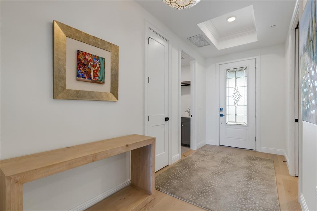 A bright entryway features a light wood console table, a patterned rug, and white doors — 505 TAMIAMI TRAIL N UNIT 501, VENICE, FL