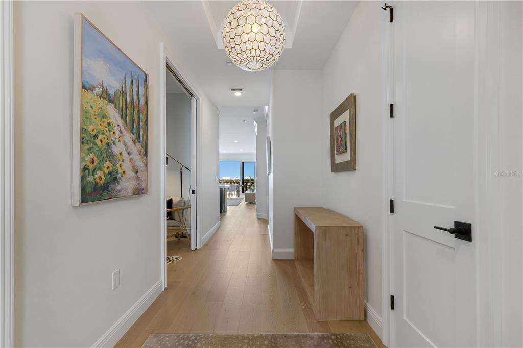 A bright hallway features light wood flooring, a decorative pendant light, and a console table — 505 TAMIAMI TRAIL N UNIT 501, VENICE, FL