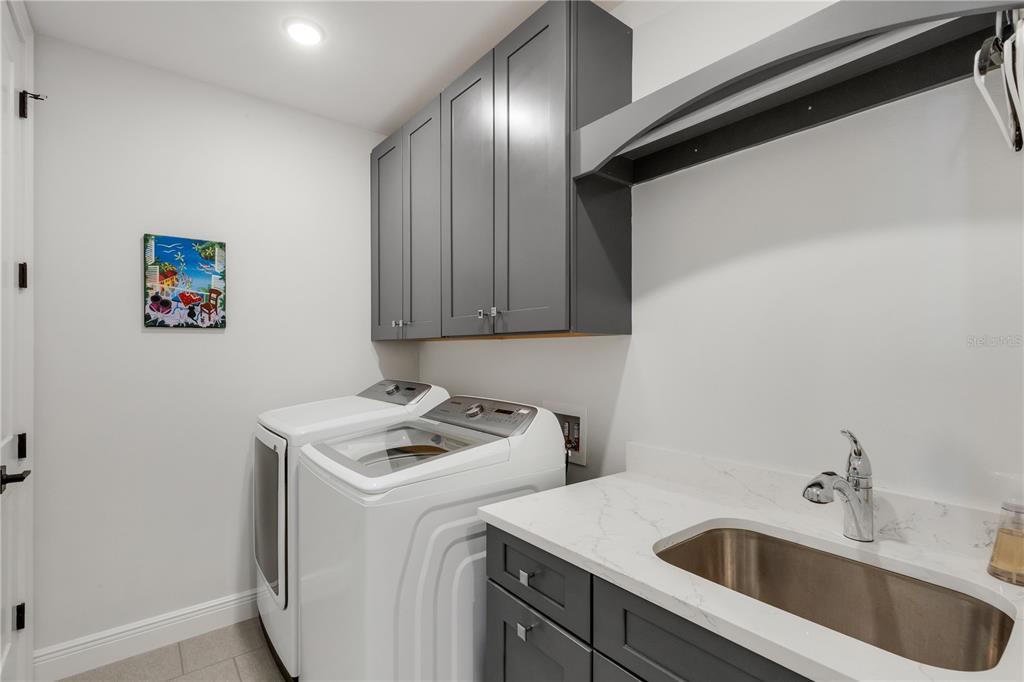 A laundry room features white appliances, gray cabinets, a sink, and white countertops — 505 TAMIAMI TRAIL N UNIT 501, VENICE, FL