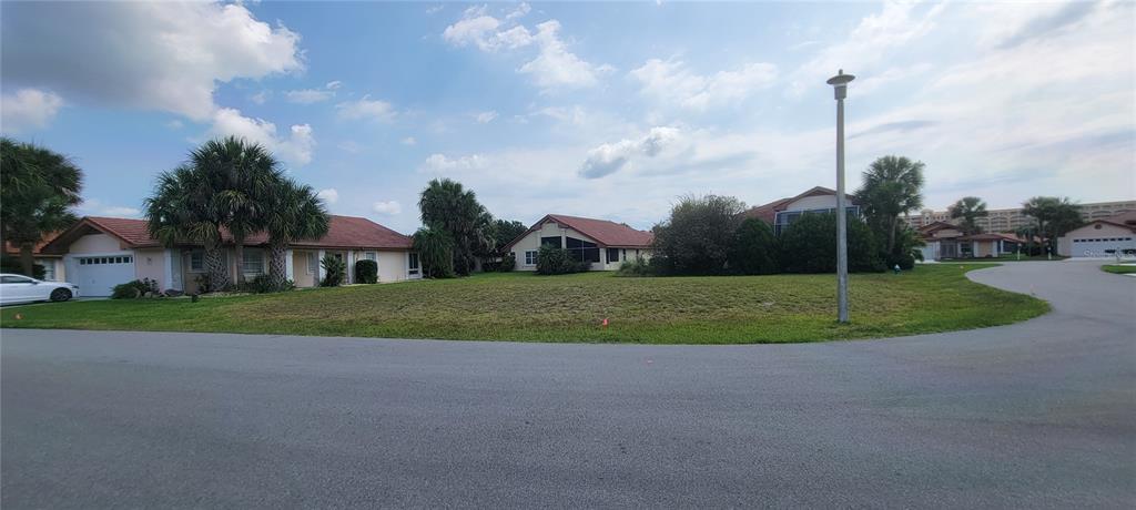 A vacant grassy lot sits between two residential houses on a paved street — 11 SAN LUIS LANE, PALM COAST, FL