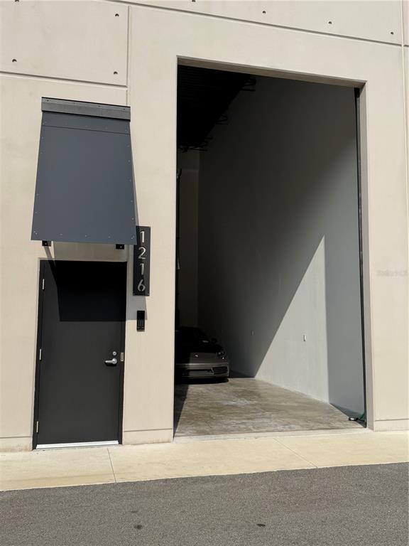 A modern industrial building exterior features a dark metal door, an awning, and an open garage — 6500 MOTOR ENCLAVE WAY UNIT 1216, TAMPA, FL