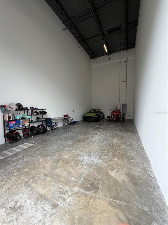 A high-ceilinged garage with concrete floors, storage shelving, a sports car, and an ATV — 6500 MOTOR ENCLAVE WAY UNIT 1216, TAMPA, FL