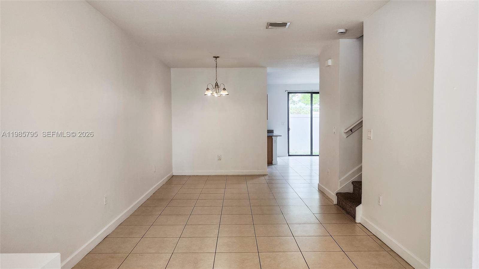 This room features tiled flooring, a dining area with a chandelier, and a staircase — 470 NE 194th Ter # 470, Miami FL 33179, MIAMI, FL