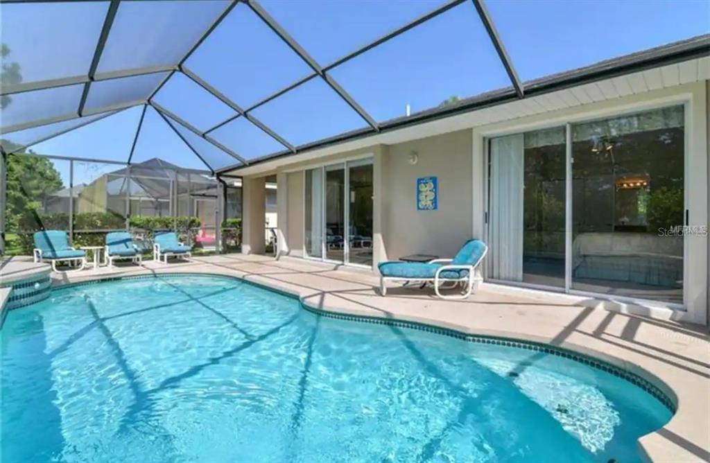 A swimming pool with a screened-in lanai and lounge chairs sits behind a residential home — 2918 SUNSET VISTA BOULEVARD, KISSIMMEE, FL