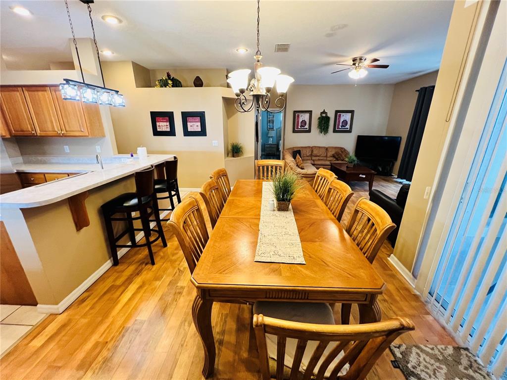 A dining room with a wooden table and chairs adjacent to a kitchen island — 2918 SUNSET VISTA BOULEVARD, KISSIMMEE, FL