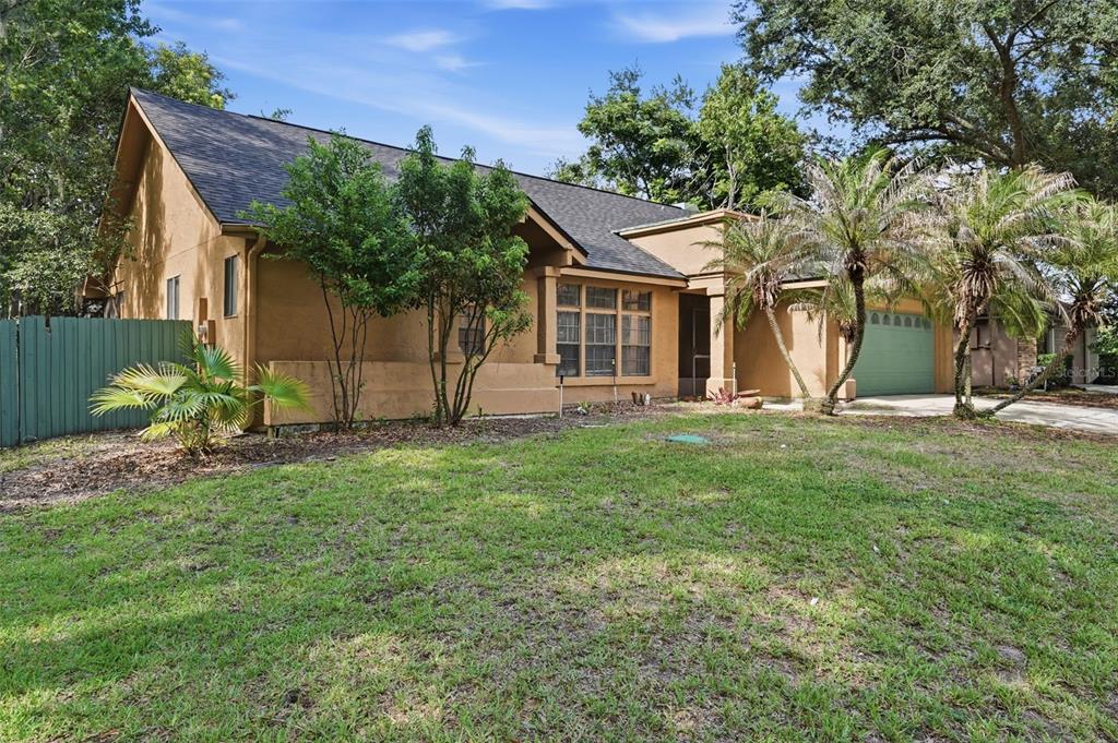 A tan, single-story house with a dark shingled roof and a green garage door — 733 SWAYING PALM DRIVE, APOPKA, FL