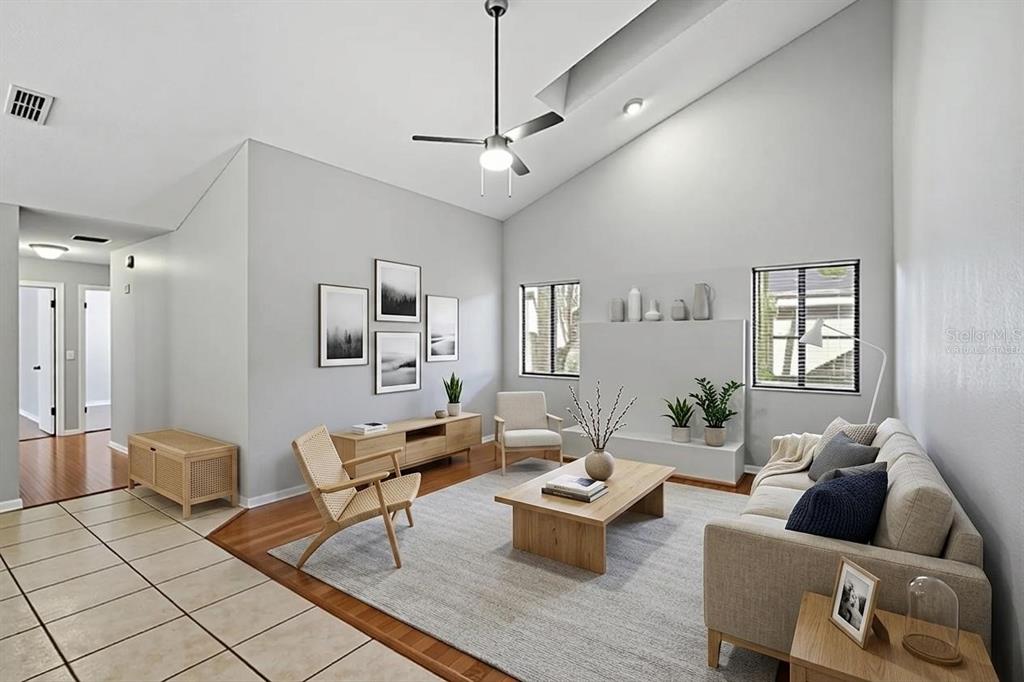 A living room with vaulted ceilings, hardwood floors, a neutral area rug, and modern furniture — 733 SWAYING PALM DRIVE, APOPKA, FL
